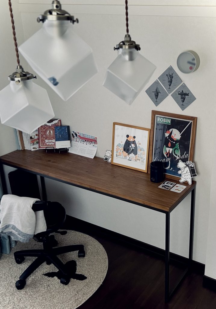 曇りガラスの照明越しに、イラストや本を飾った長机を撮った写真。